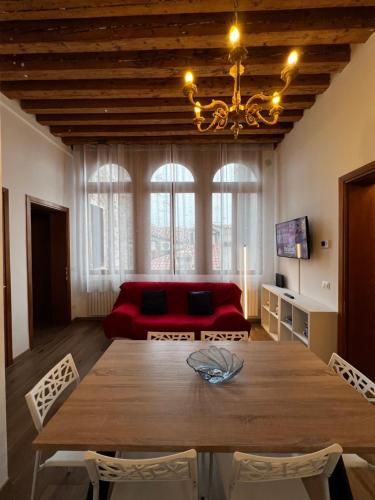 ein Esszimmer mit einem Tisch und einem roten Sofa in der Unterkunft TINTORETTO 1 CON TERRAZZA SOPRA IL TETTO, 3 bagni, 3 grandi camere da letto, SUPER NUOVO in Venedig