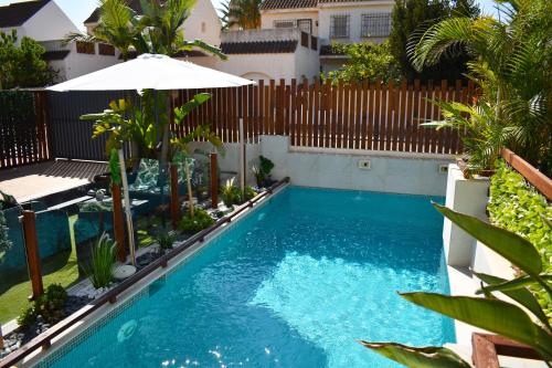 ein Pool mit einem Sonnenschirm und einem Zaun in der Unterkunft Alaïa Apartamentos in Playa Paraiso