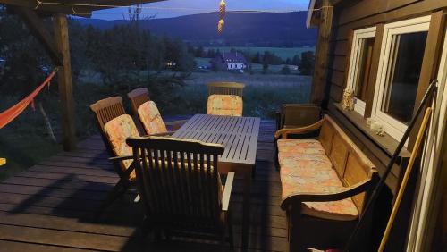 - une table et des chaises en bois sur une terrasse couverte avec vue dans l'établissement Domek z widokiem na góry Lasówka, à Bystrzyca Kłodzka