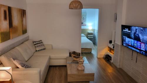 sala de estar con sofá y TV de pantalla plana en Apartamento EL REAL - Espartinas - SEVILLA, en Espartinas