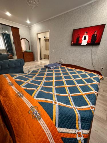 - une chambre dotée d'un lit avec une couverture orange et bleue dans l'établissement 1 ком квартира, à Aket