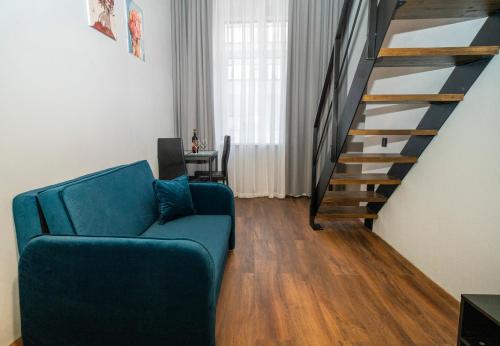 ein Wohnzimmer mit einem blauen Sofa und einer Treppe in der Unterkunft Teeny Tiny Lofts in Center in Kaunas