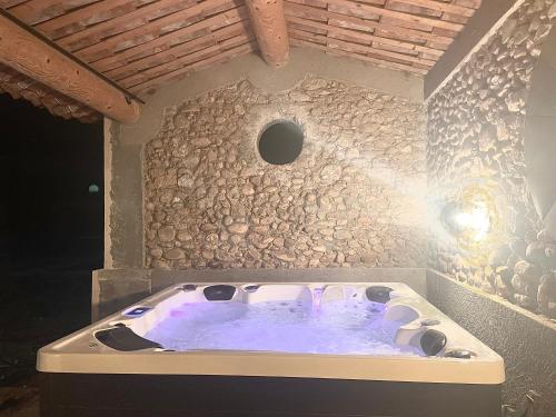 Les Mazets Du Pas في جيرو-لي-بان: حوض استحمام ساخن في غرفة بجدار حجري