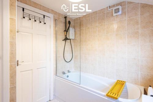 a bathroom with a white tub and a shower at 3 bedroom House - Next to Wrexham FC Racecourse Stadium in Wrexham