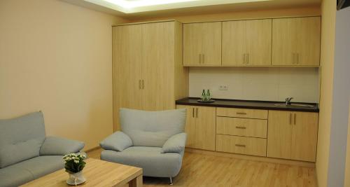 ein Wohnzimmer mit 2 Stühlen und einem Tisch sowie eine Küche in der Unterkunft Hotel Klaudia in Juszczyn
