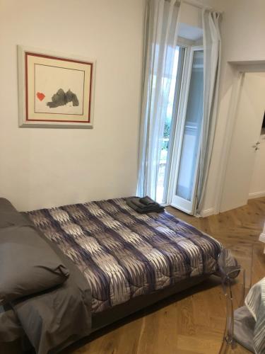 a bed in a room with a large window at sonnino house in Pisa