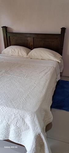 uma cama com lençóis brancos e uma cabeceira de madeira em Paradise Rio Celeste 2 em Bijagua