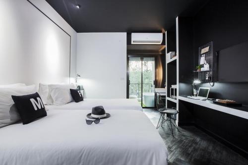 un dormitorio con una cama blanca con sombrero en Blu Monkey Hub and Hotel Phuket - SHA Extra Plus en Phuket