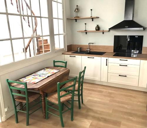 une cuisine avec une table, des chaises et un évier dans l'établissement Maison de vacances, à Châtelaillon-Plage
