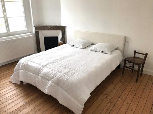 une chambre avec un grand lit blanc et une chaise dans l'établissement Maison de vacances, à Châtelaillon-Plage