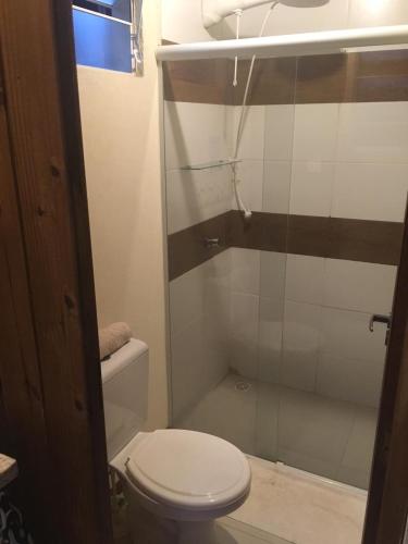 a bathroom with a toilet and a glass shower at Casas Paz e Amor Praia do Rosa Sunset e Sunrise in Imbituba
