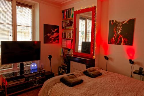 une chambre avec un lit, une télévision et un miroir dans l'établissement Paris Appartement au cœur du Marais, à Paris