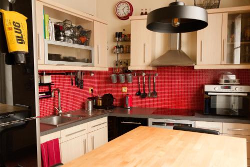 - une cuisine avec des placards blancs et un mur en carrelage rouge dans l'établissement Paris Appartement au cœur du Marais, à Paris