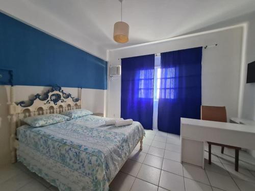 a bedroom with a bed and a desk and a blue wall at Pousada casa amarela in Salvador