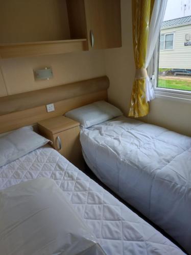2 Betten in einem kleinen Zimmer mit Fenster in der Unterkunft Swift johnson in Parkeston