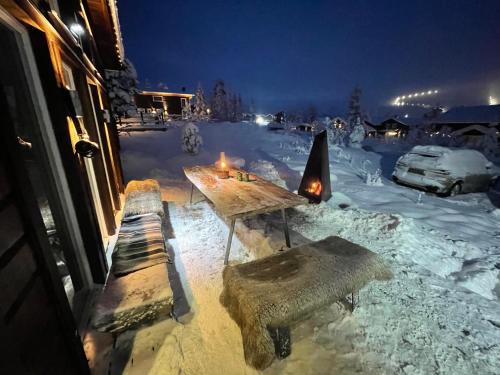 un patio cubierto de nieve con mesa de madera y bancos en Granfjällsporten 57, en Stöten