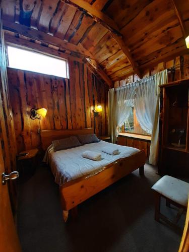 a bedroom with a bed in a wooden cabin at Hosteria-Cabañas Rucapillan in Choshuenco