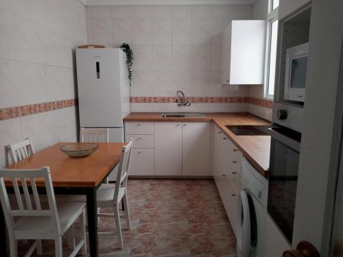ラスパルマス・デ・グランカナリアにあるAmplio apartamento a 50 metros de la Playaのキッチン(木製テーブル、白い冷蔵庫付)