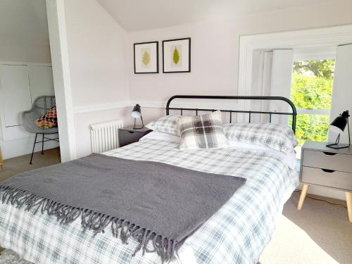 a bedroom with a bed with a plaid blanket at Lochside cottage with scenic terrace views, Argyll in Clynder