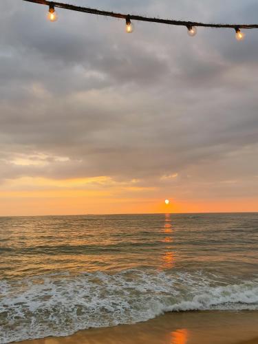 a sunset over the ocean with lights on the beach at Maike Cabana in Boossa