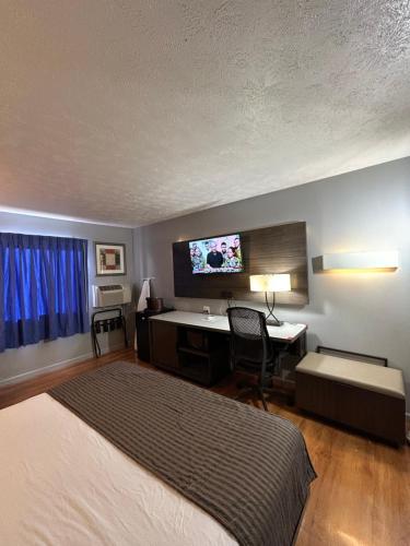 Un dormitorio con una cama, un escritorio y un televisor. en Rodeway Inn, en Emporia