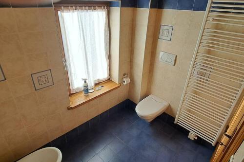 uma casa de banho com um WC e uma janela em In cima alla contrada em Pieve di Cadore