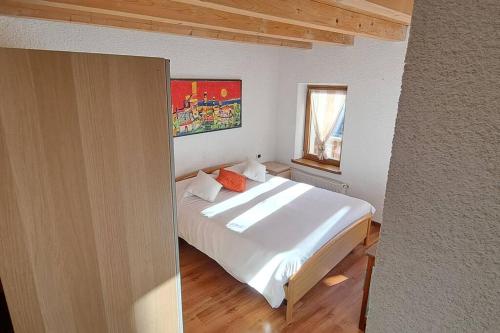 ein Schlafzimmer mit einem weißen Bett und einem Fenster in der Unterkunft In cima alla contrada in Pieve di Cadore