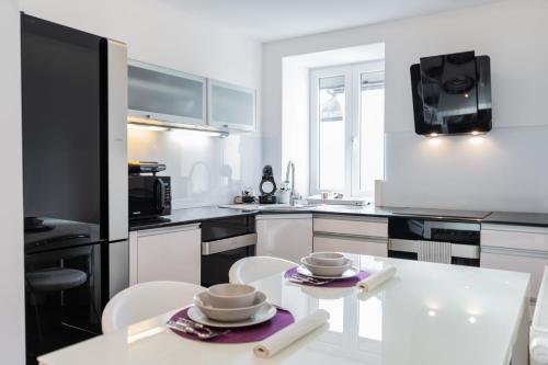 a white kitchen with a white table and chairs at Celje Center Apartment in Celje
