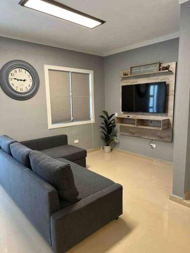 a living room with a couch and a clock and a tv at Palmas View Premium 7 in Humacao