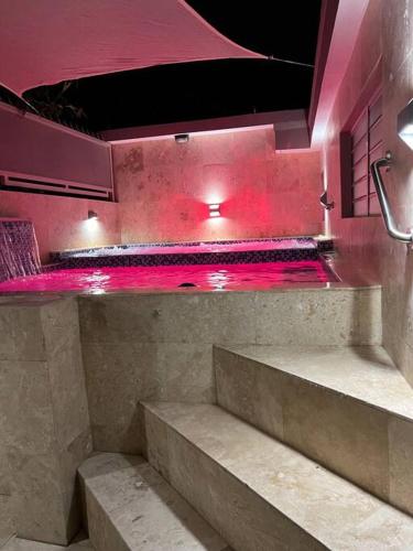 a swimming pool with stairs in a room with pink lights at Palmas View Premium 7 in Humacao