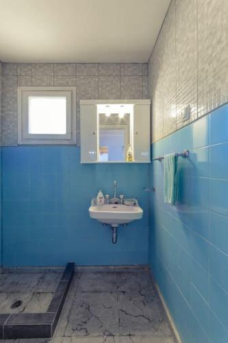a blue bathroom with a sink and a mirror at Beautiful cottage house at Mesokampos in Samos