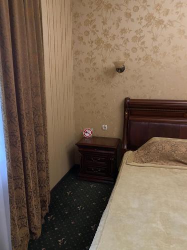 a bedroom with a bed and a nightstand next to a window at Status Hotel in Poltava