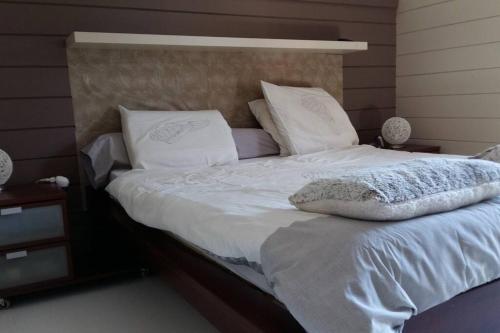 Una cama con sábanas blancas y almohadas. en Dans un parc privatif arboré, en Réau