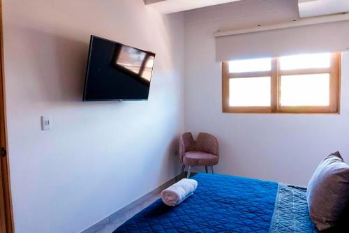 Schlafzimmer mit einem Bett, einem TV und einem Stuhl in der Unterkunft Apartamento 402 - Terraza con Jacuzzi - 3 Habitaciones - Rentas Cortas Gerencial in Guatapé