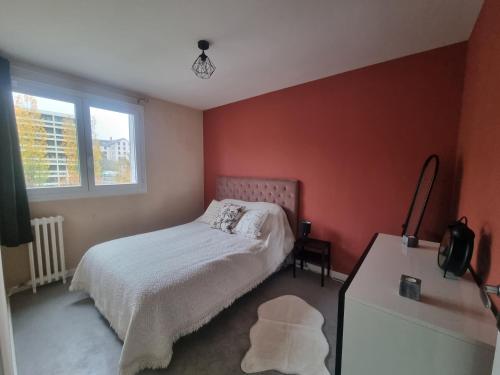 Appartement Aurillacois في أوريلاك: غرفة نوم بجدران حمراء وسرير وطاولة