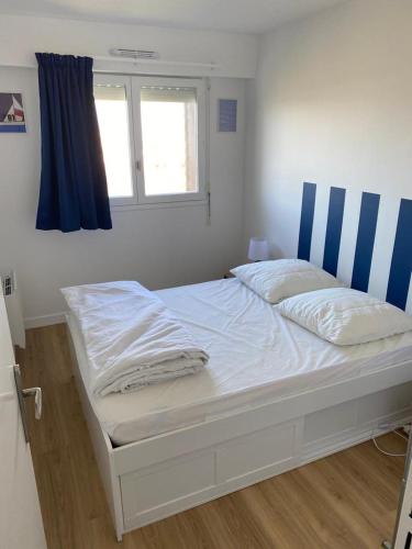 un lit blanc dans une chambre avec une fenêtre dans l'établissement T2 refait à neuf, à Cabourg