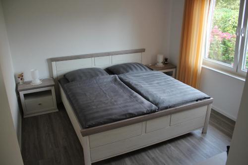 een bed in een slaapkamer met 2 tafels en een raam bij Ferienwohnung "TimeOut" in Hage