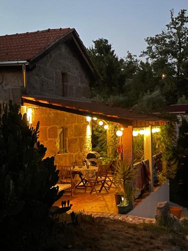a house with a patio with a table and lights at Quinta do Cobral in Oliveira do Hospital