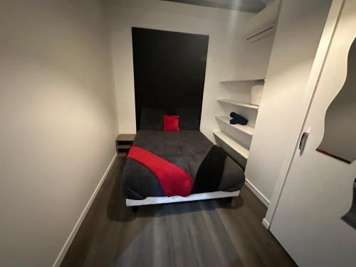 ein kleines Schlafzimmer mit einem Bett mit einem roten Kissen in der Unterkunft Love room borabora 6 in Trévoux