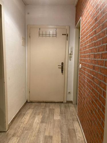 een lege kamer met een witte deur en een bakstenen muur bij Schöne Dachgeschosswohnung in Essen