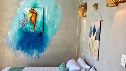 a bedroom with a seahorse painting on the wall at SHANTI SURF CAMP in El Paredón Buena Vista