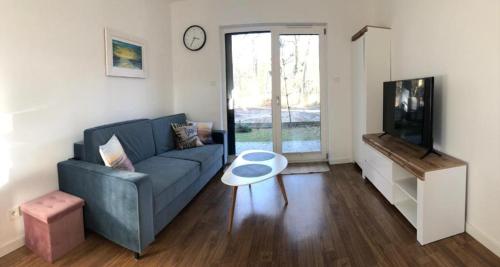 a living room with a blue couch and a tv at Apartament Nad Liwką in Niechorze