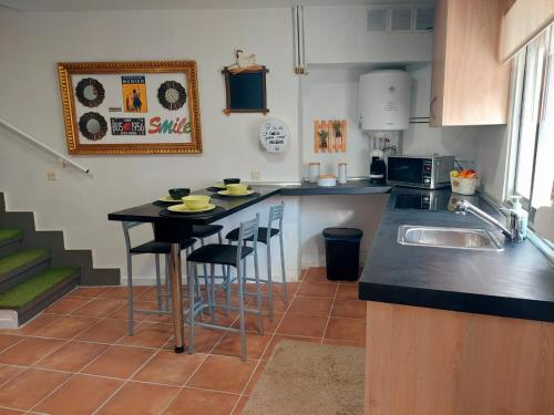 a kitchen with a sink and a counter with stools at Casa Mencía in Camponaraya