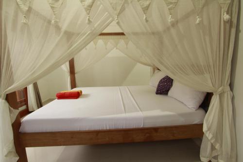 a bedroom with a bed with white drapes at Suryadina Guest House in Ubud