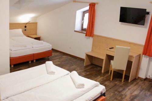 Habitación con 2 camas, escritorio y TV. en Ski Lodge Pampeago, en Tesero