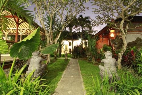 a garden with statues in front of a house at Suryadina Guest House in Ubud