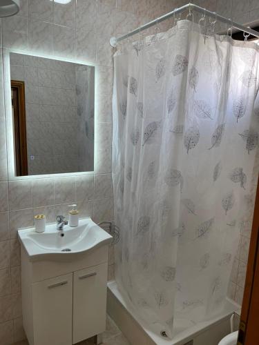 a bathroom with a sink and a shower curtain at Hills Holiday House in Mostar