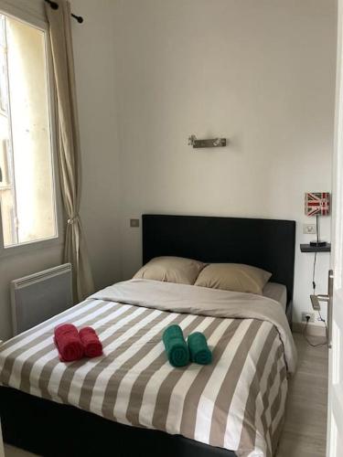 dos zapatillas en una cama con una manta a rayas en T3 centre ville Historique, en Aix-en-Provence