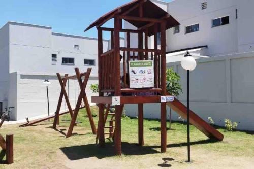 a wooden playground with a sign in the grass at Apartamento top bem localizado in Vitória da Conquista
