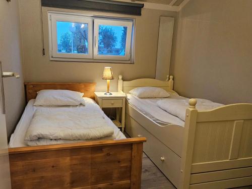 two twin beds in a bedroom with a window at Duinenhuis Zeepolder 27 in De Haan